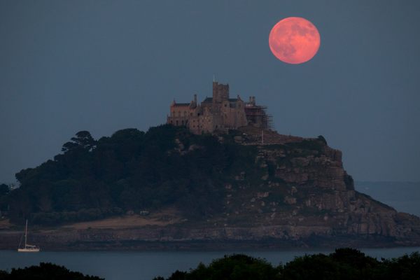 The 2018 Strawberry Moon rises behind St. Michael's Mount in Cornwall, England. While increased humidity in the atmosphere may turn these early summer full moons pinkish, their name originates with the ripening time of strawberries in North America.